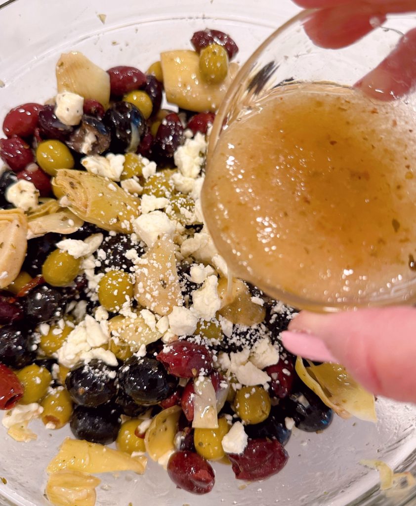 Adding feta cheese and Greek salad dressing to marinated olives..