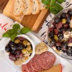 Overhead shot of marinated olives on a cheeseboard.