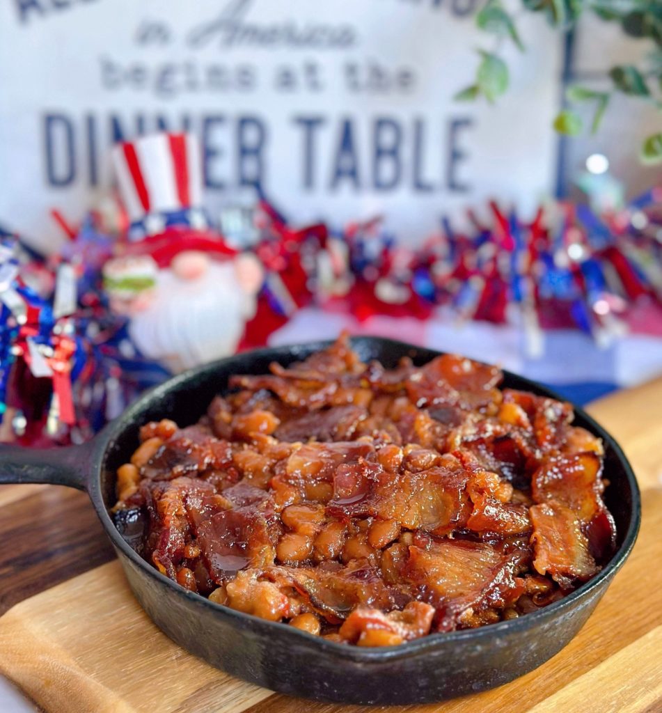 Oven baked beans in a small skillet with 4th of July decorations in the background.