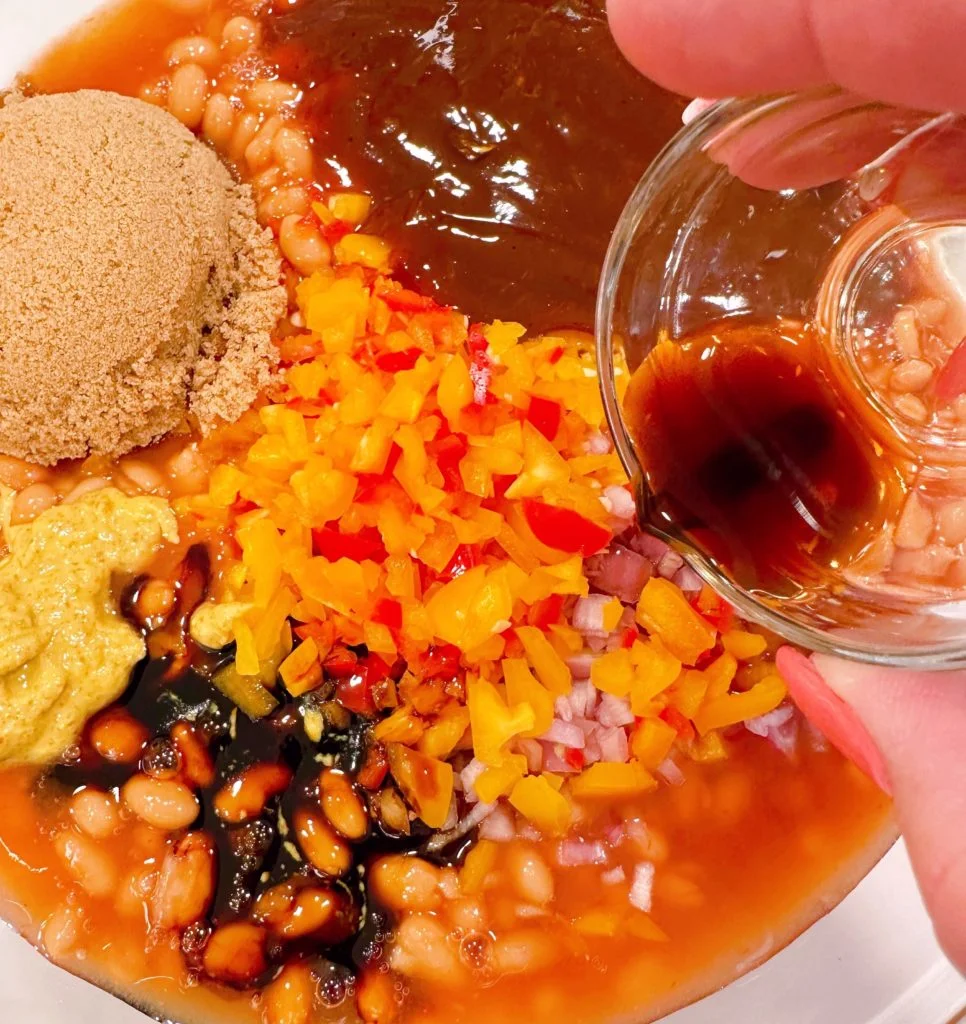 Adding Worcestershire sauce to the bake bean mixture.