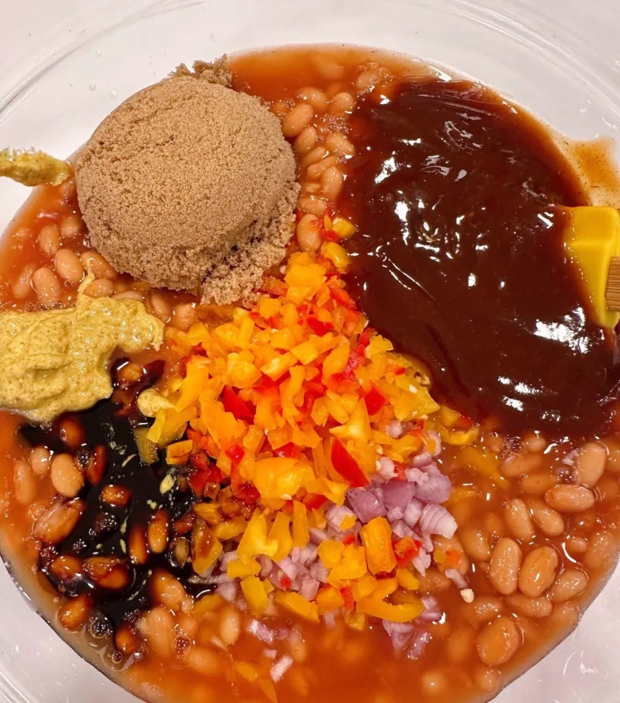 Ingredients for baked beans in a large bowl.