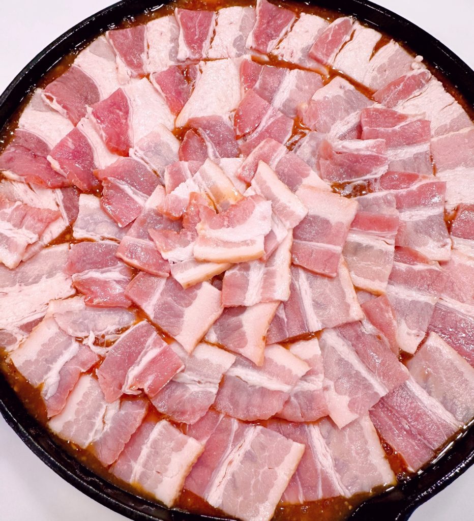 Bacon covering the top of the baked beans.
