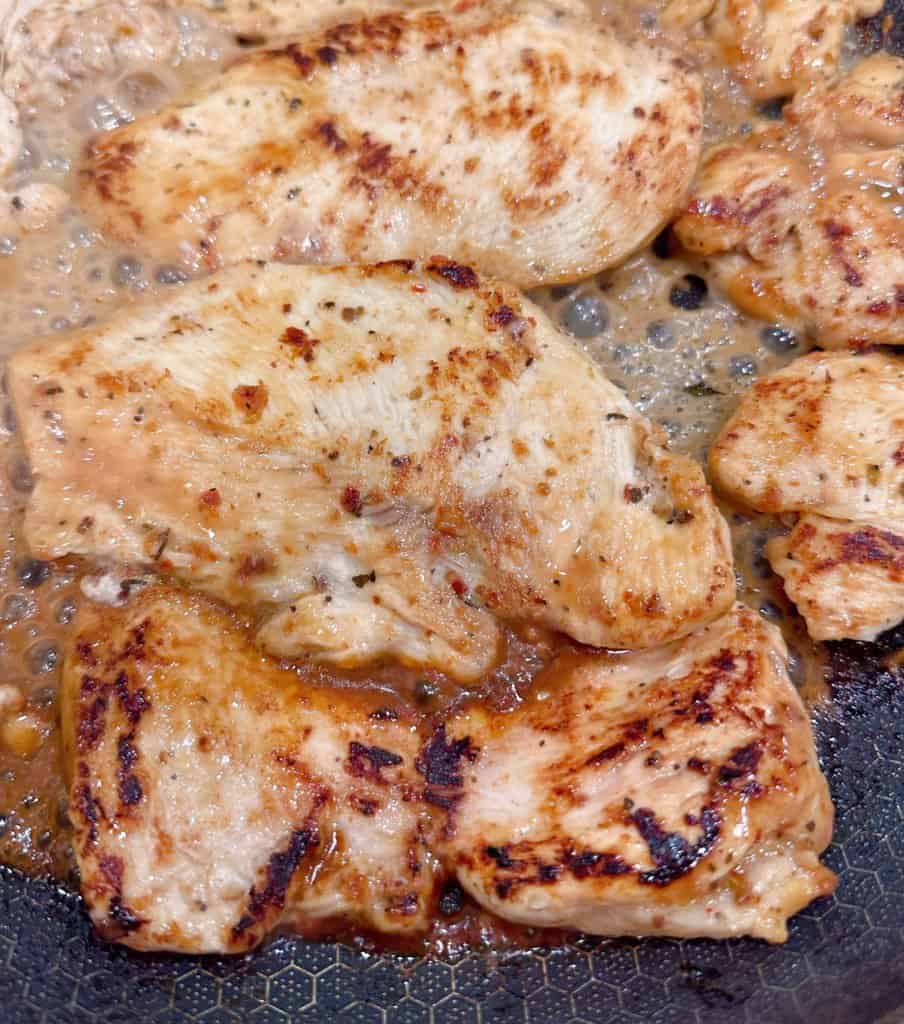 Cooking chicken in a skillet on the stovetop. 