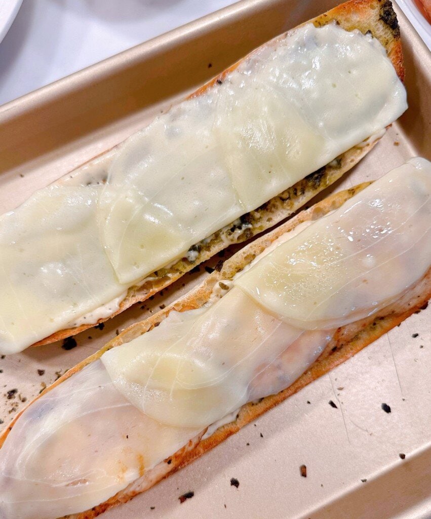 Melted cheese on top of chicken and baguette.