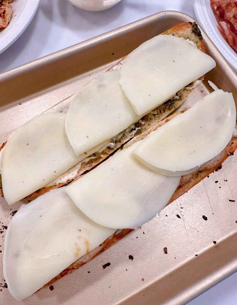 Cheese slices on top of baguette and chicken.