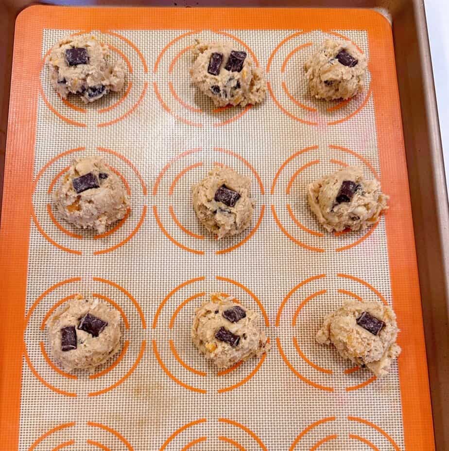 Cookie dough scoopfuls on a lined cookie sheet.