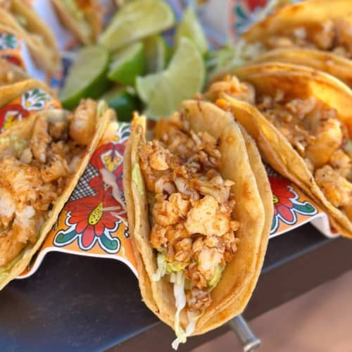 Fresh finished tilapia tacos with cabbage and fresh limes.