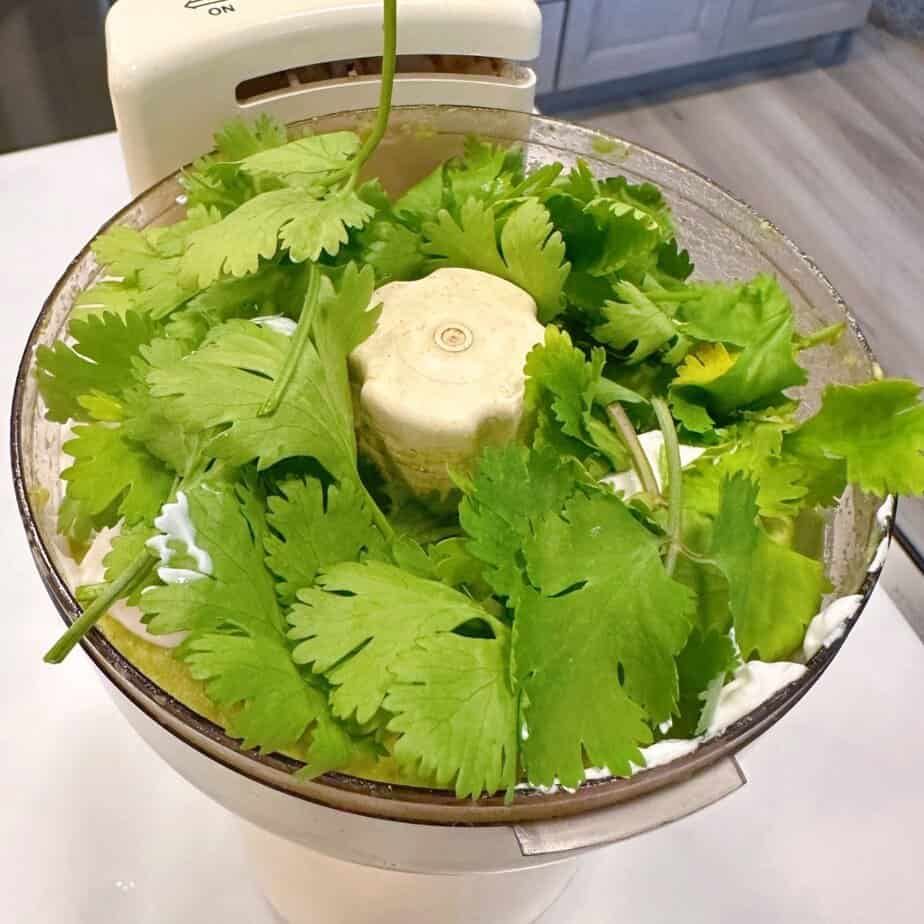 Adding cilantro to avocado crema.
