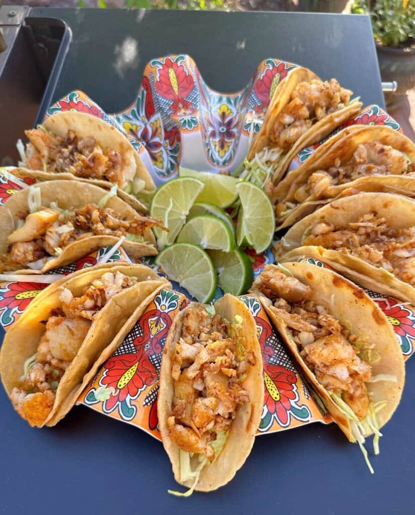 Tacos filled with cooked tilapia in a taco holder.