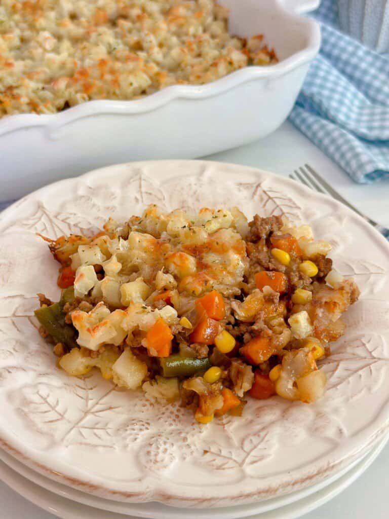 Layered Beef and Potato Casserole served on a plate with the casserole in the background.