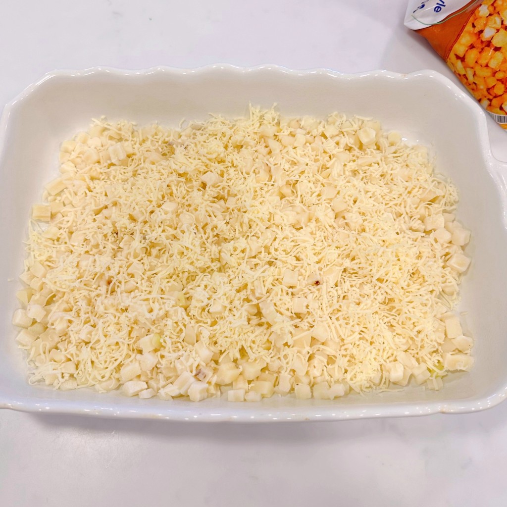 Layering casserole starting with potatoes and half the cheese.