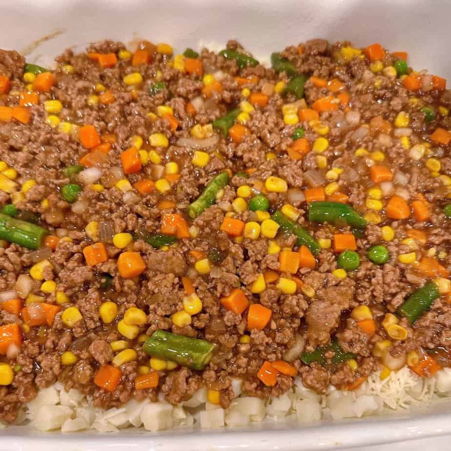Meat mixture on top of cheese and potatoes.
