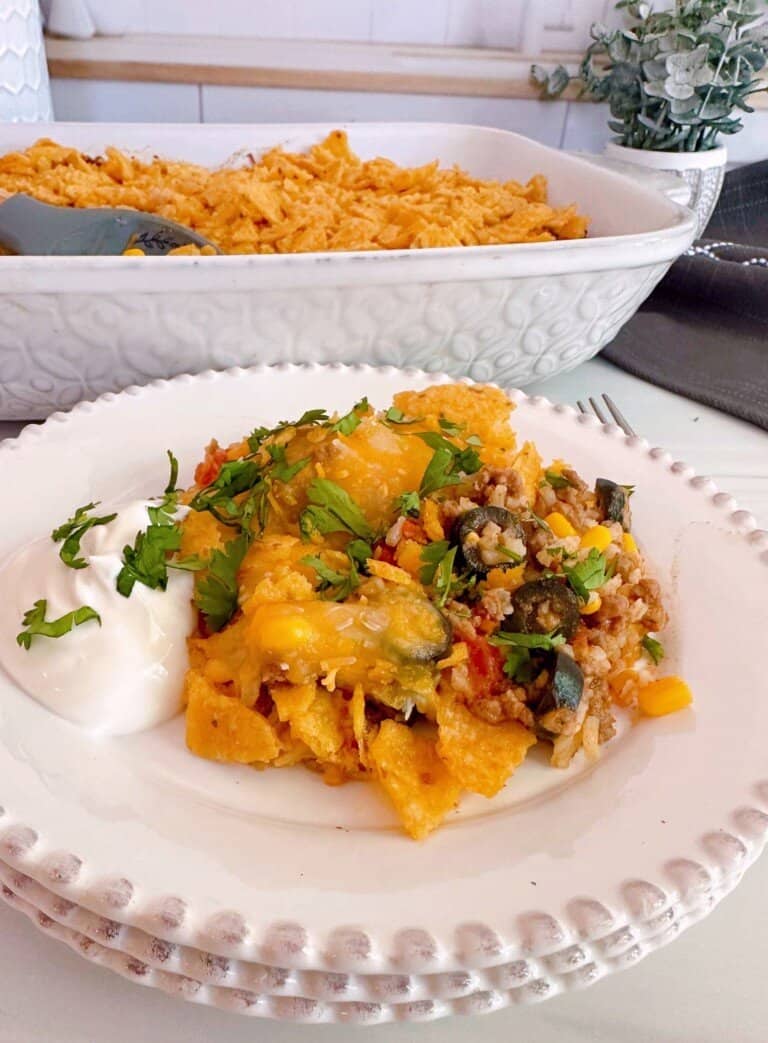 Cheesy Taco Rice Casserole with sour cream and cilantro with the full casserole in the back ground.