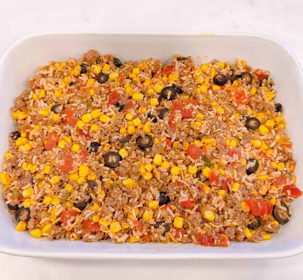 Cheesy Taco Casserole ingredients in prepared casserole dish.