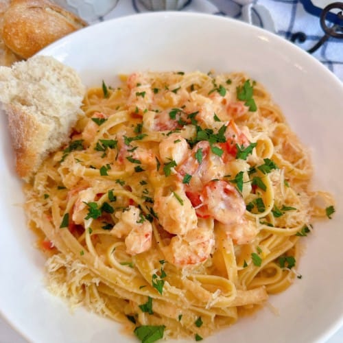 Lobster Bisque Pasta in a white bowl with a piece of crusty bread.