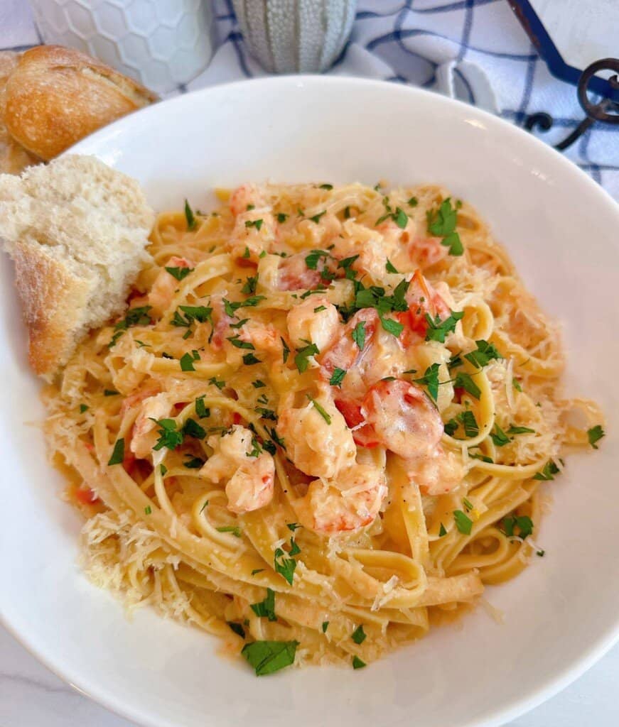 Lobster Bisque Pasta in a white bowl with a piece of crusty bread.