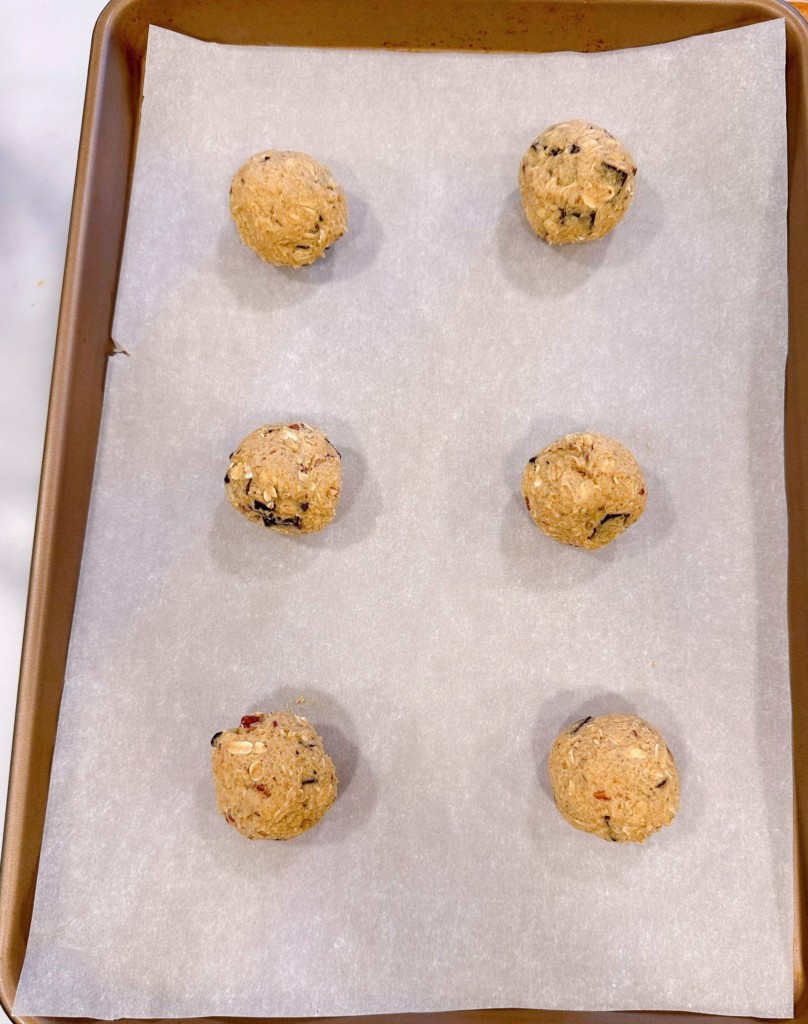 Cookie dough arranged on cookie sheet, rolled into balls.