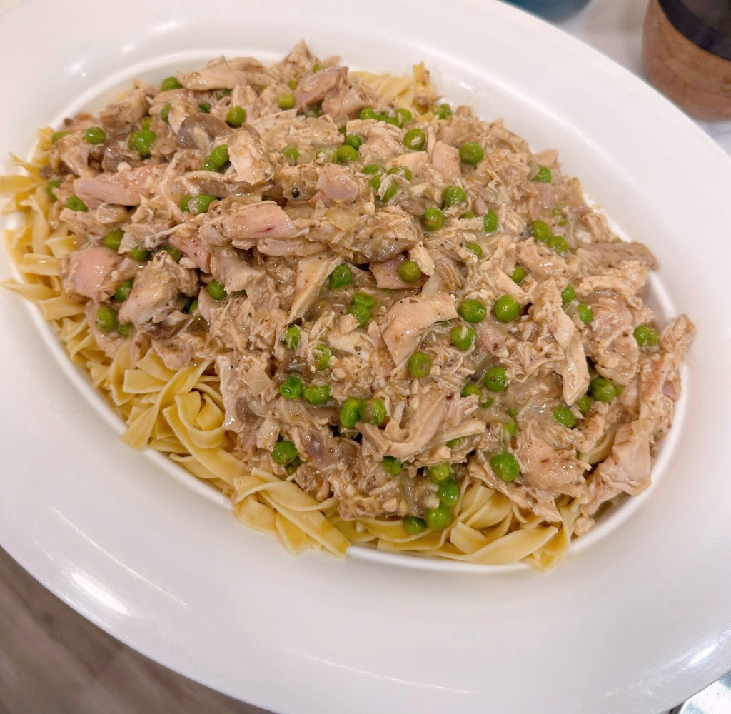 Pouring chicken sauce over pasta.