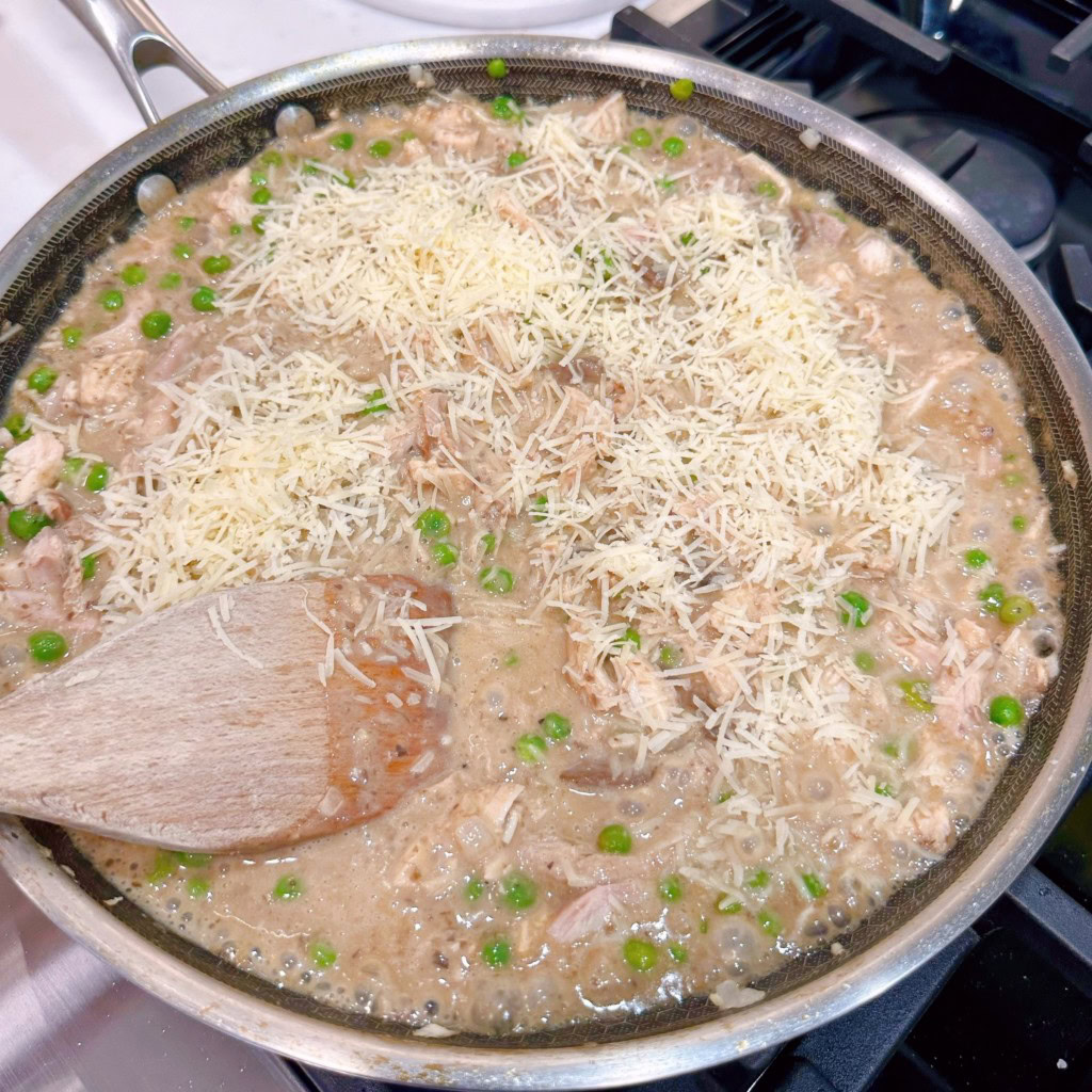 Adding half of the grated parmesan cheese to chicken mixture.