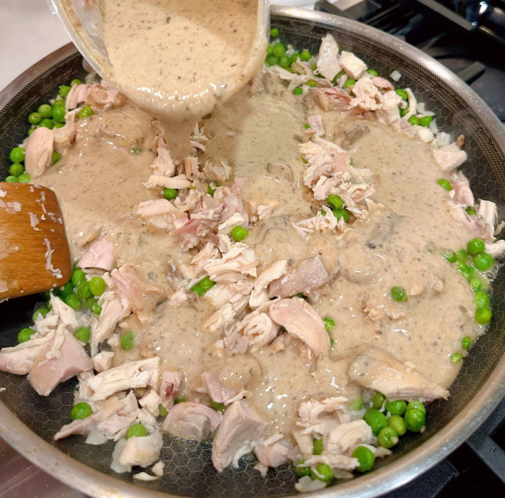 Adding prepared soup to create sauce for pasta.