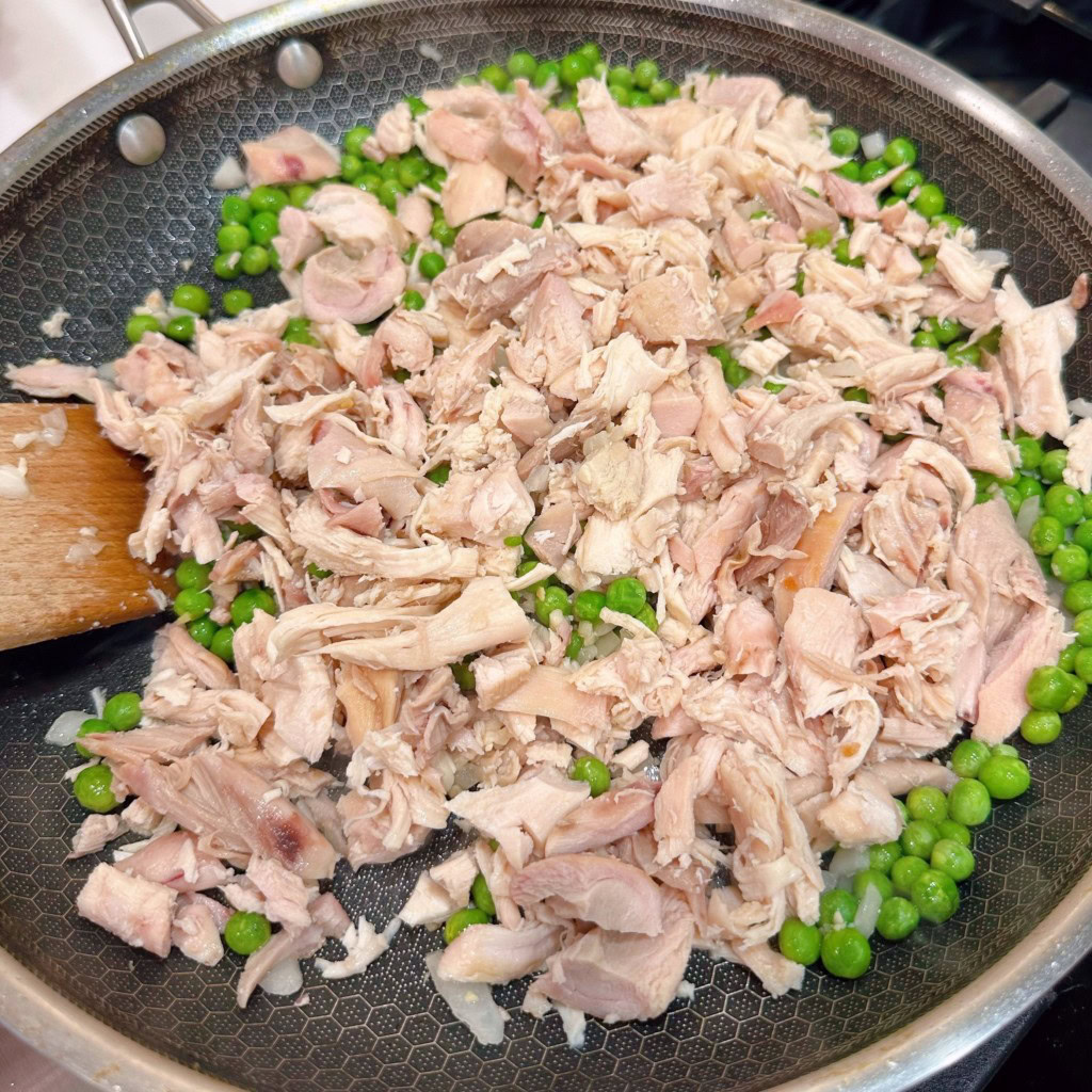 Adding chicken to peas and onions.