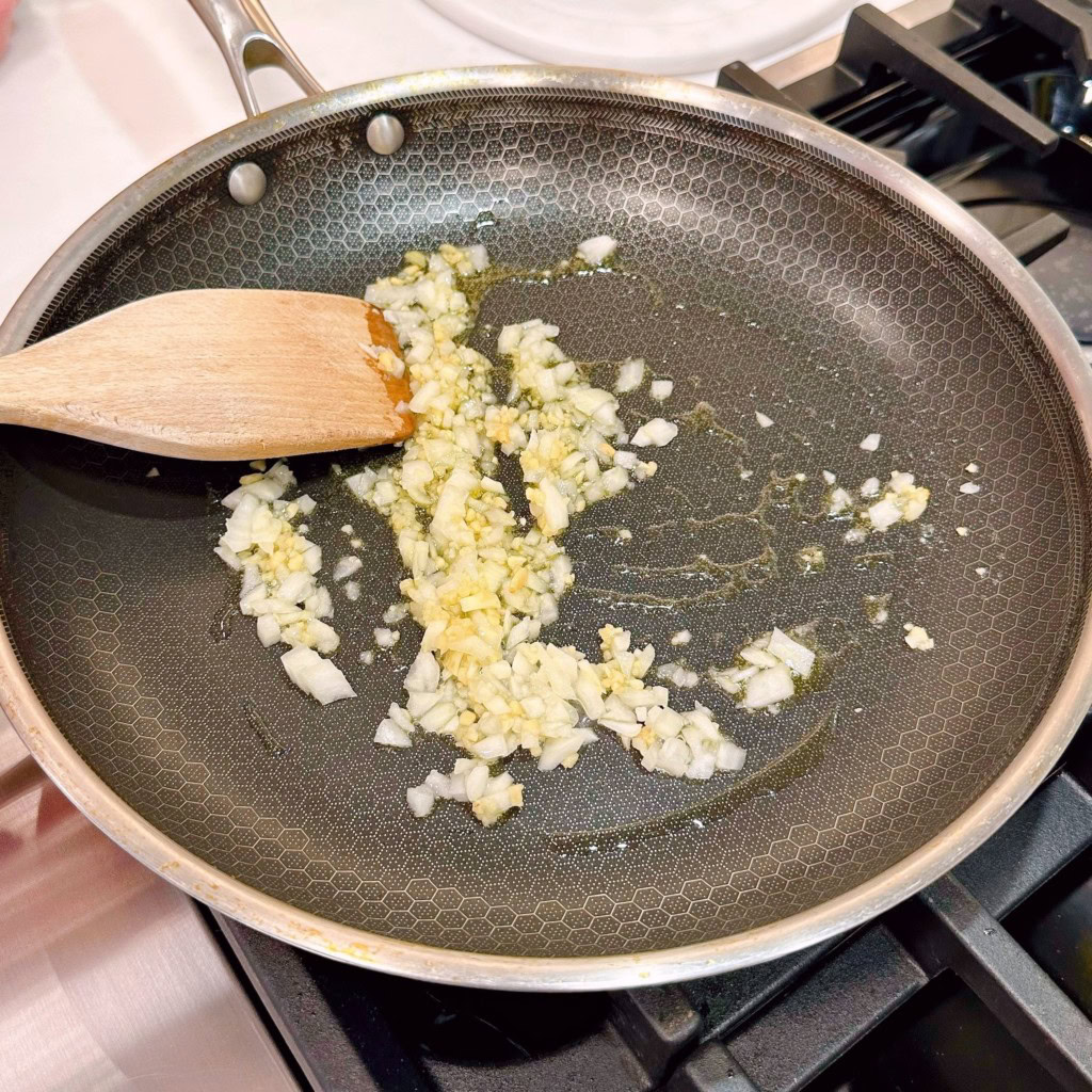 Sauting onions and garlic in a large skillet with olive oil.