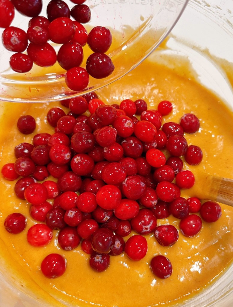 Adding cranberries to pumpkin batter.
