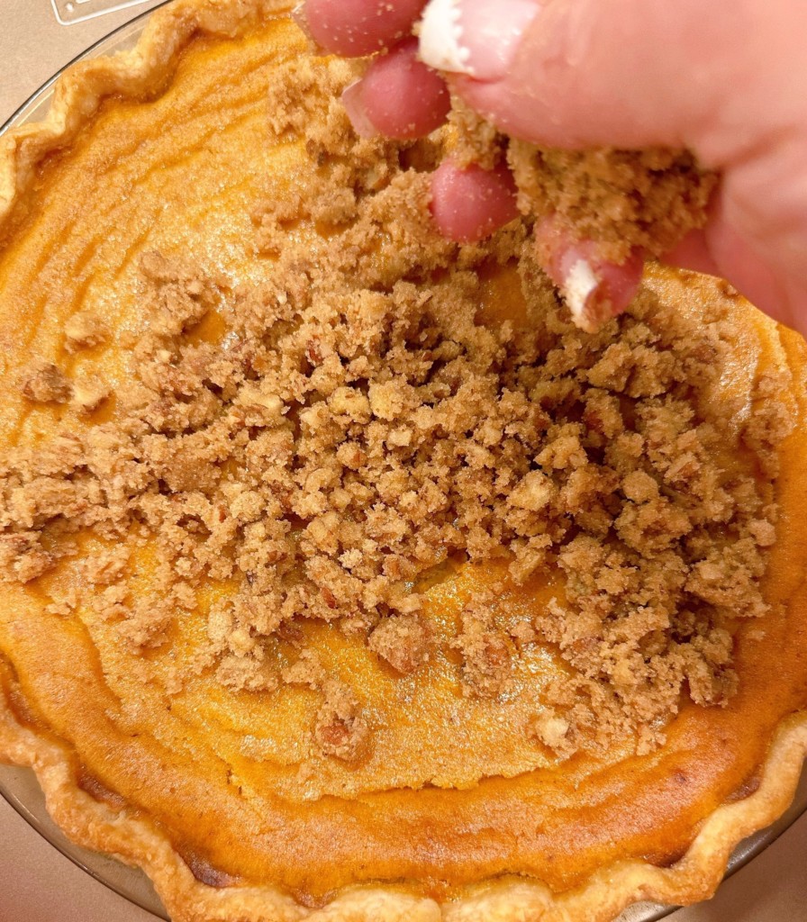 Adding pecan topping to the top of the sweet potato pie.