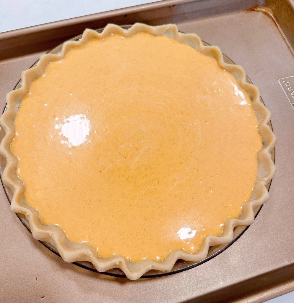 Pie filling poured into unbaked pie shell and placed on a baking sheet.