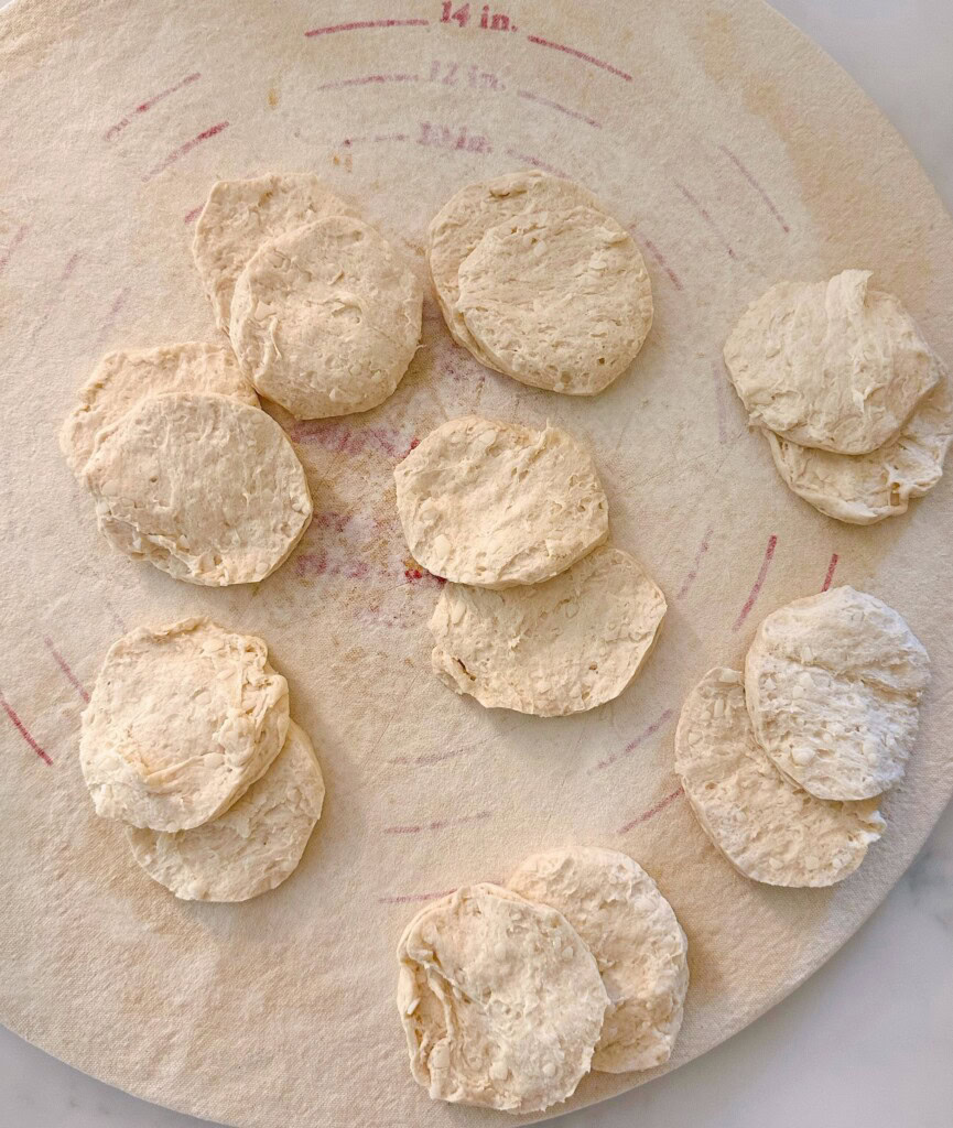 Each biscuit separated in half and laying on a floured bread board.