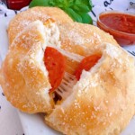 Biscuit Pizza Pockets on a plate with one broken open to reveal pepperoni and cheese.