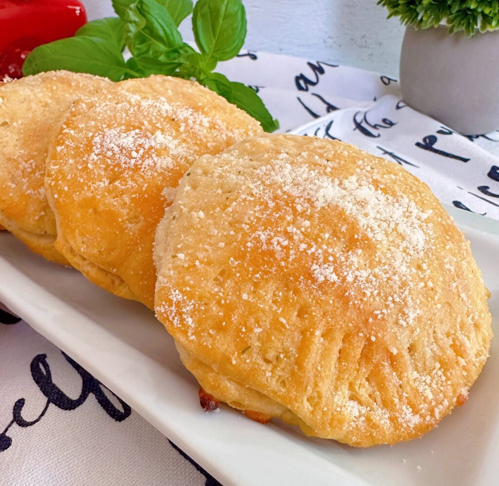 Each biscuit pizza sprinkled with Parmesan Cheese and on a plate.