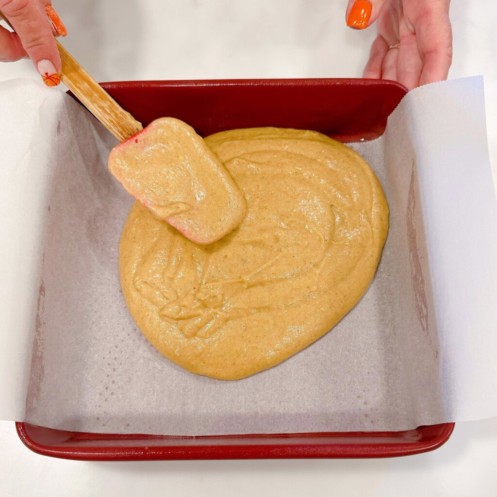 Spreading cake batter in a prepared cake pan.