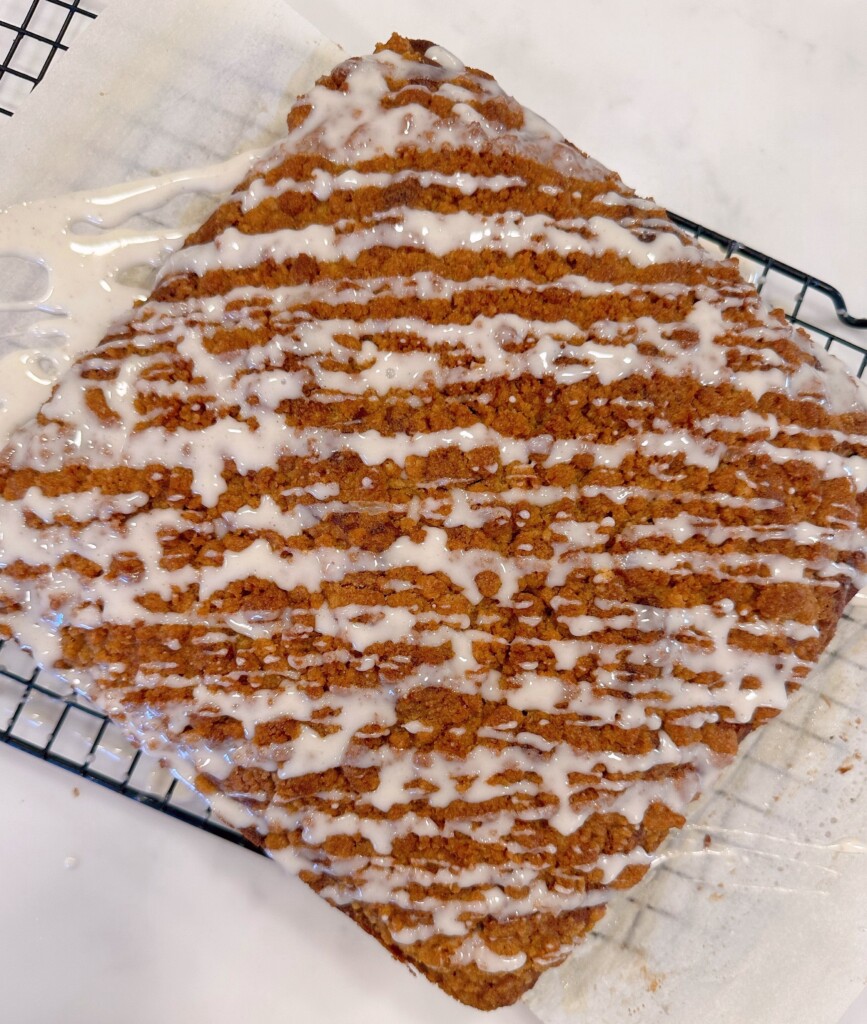 Cake drizzled with vanilla bean glaze on a cooling rack.