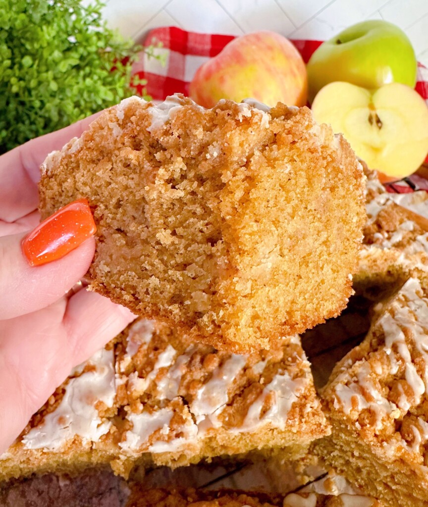 Slice of apple cider cake being held in author's hand.