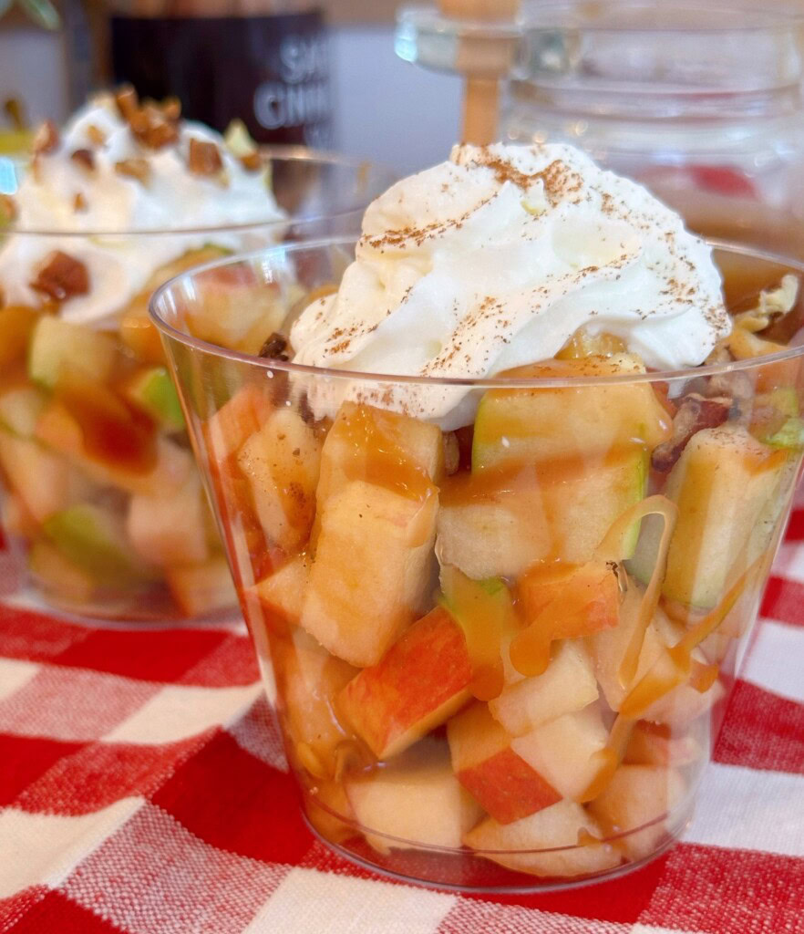 Caramel Apple in a cup topped with whipped cream and sprinkled with nutmeg.