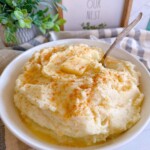 Homemade mashed potatoes in a large serving bowl with butter and a sprinkle of paprika.