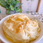 Mashed Potatoes in a large serving bowl with butter on top.