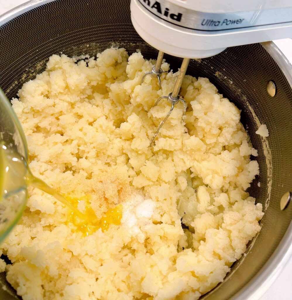 Adding the melted butter to the mashed potatoes.