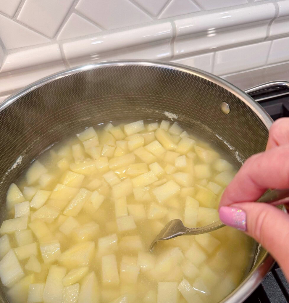 Cooked potatoes being poked with a fork for doneness.