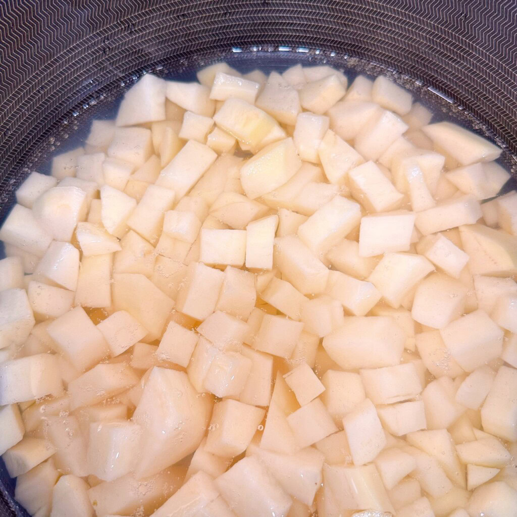 Peeled potatoes in a large stock pot covered with water.