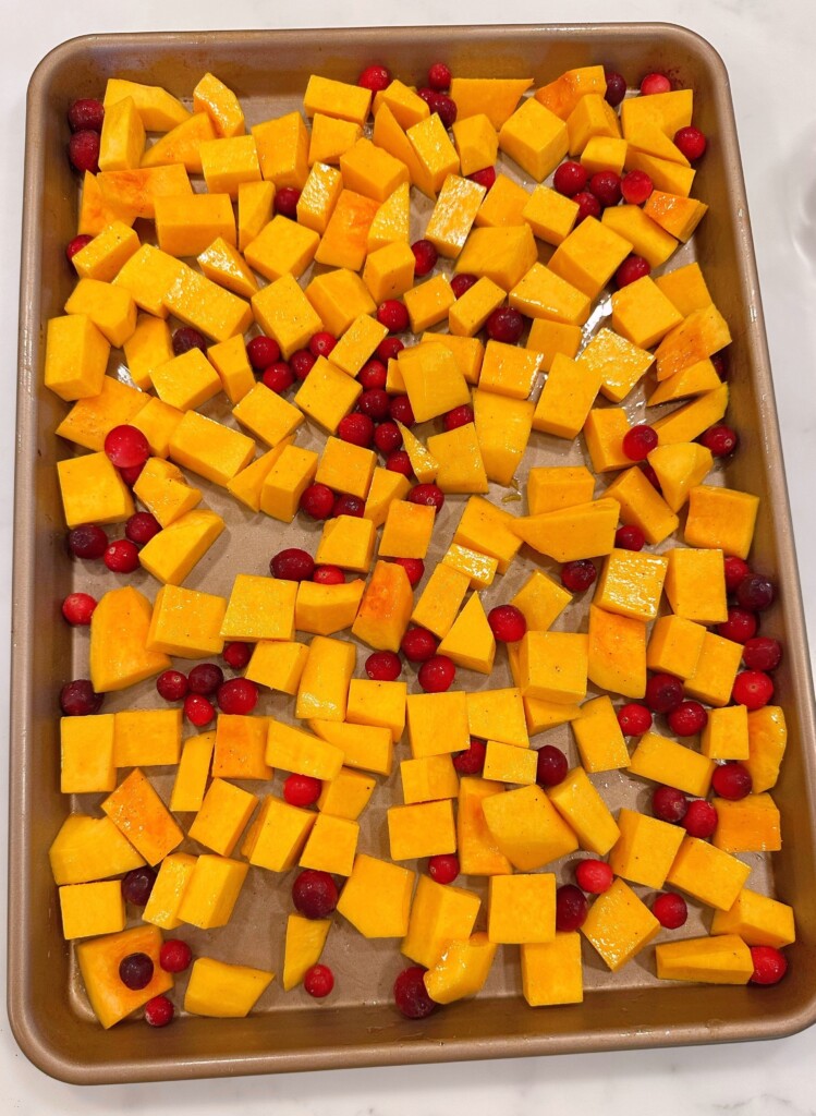 Squash and cranberries on a large baking sheet pan.