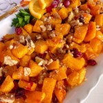 Roasted butternut squash with cranberries on a serving plate.