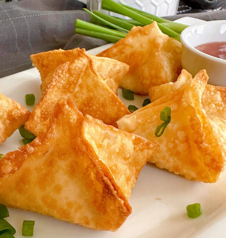 Cream Cheese Rangoons on a serving plate with chopped green onions.