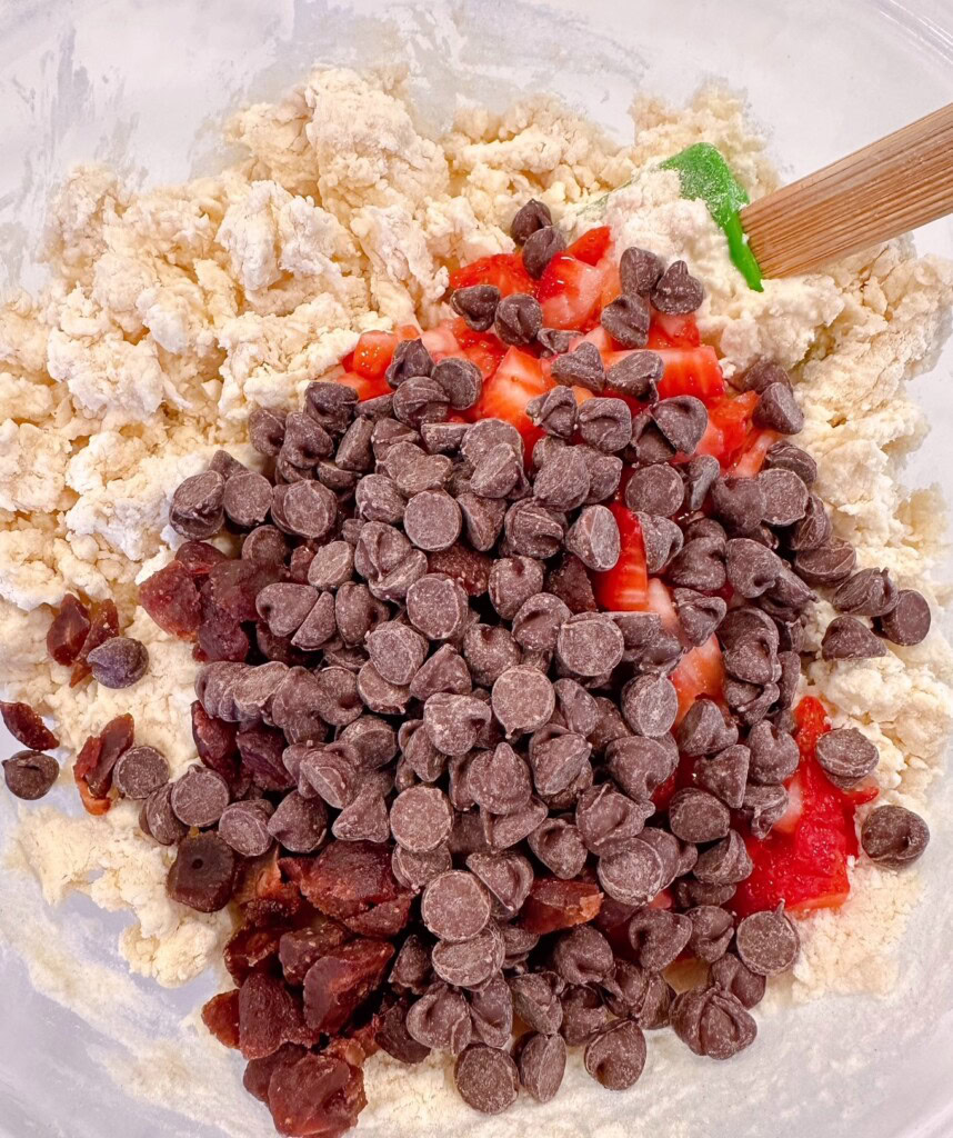 Adding strawberries and chocolate chips to scone dough.