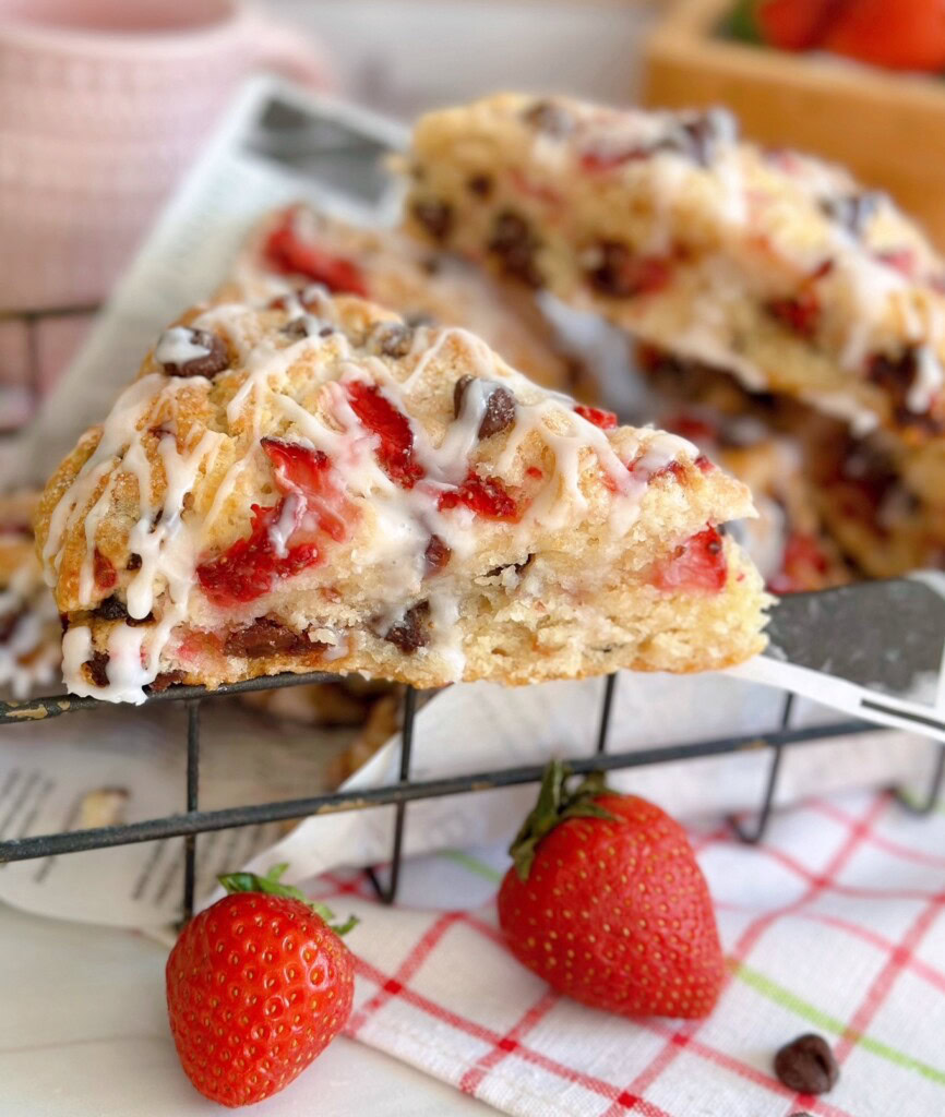 Strawberry Chocolate Chip Scones in a basket with fresh strawberries surrounding it.