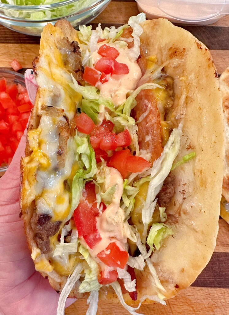 Finishing Smash burger quesadilla's with shredded lettuce, secret sauce and tomatoes.