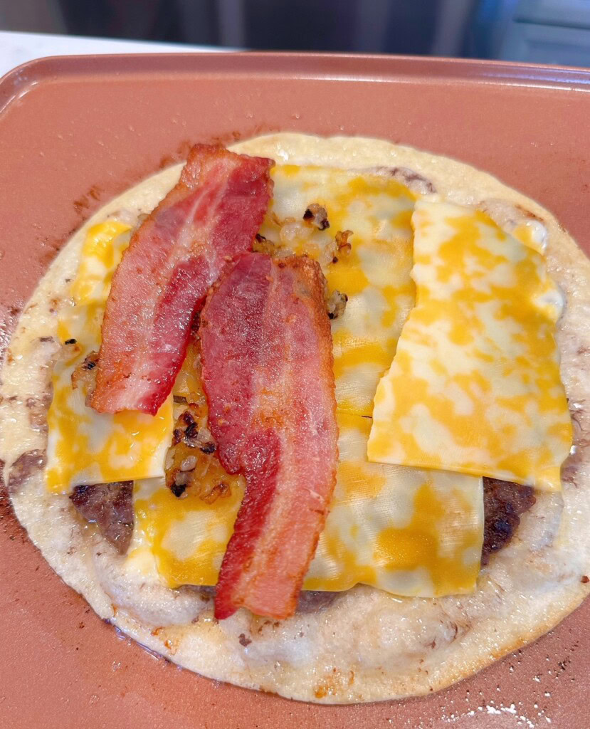 Adding bacon to the cheese burger quesadilla.
