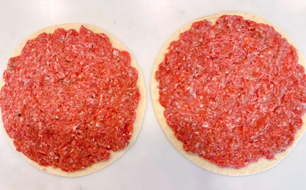 Ground beef pressed onto the outer edge of the flour tortilla.