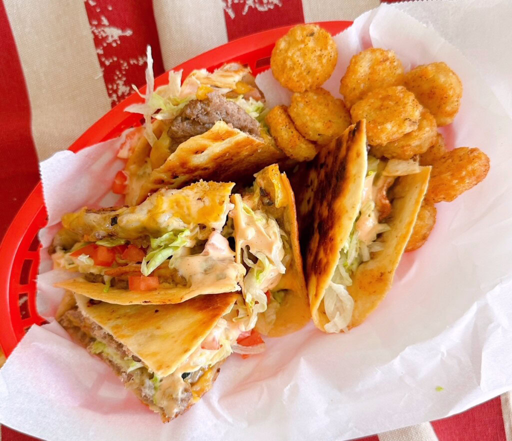 Overhead shot of the quesadilla burger stacked in a basket with tater tots.